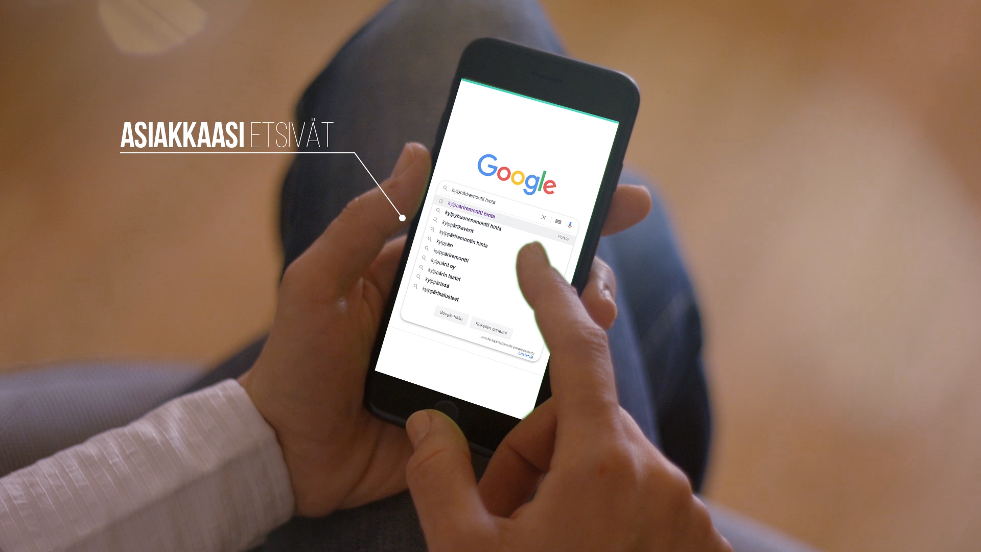 Käsissä oleva puhelin, jonka näytöllä näkyy Googlen hakusivu.